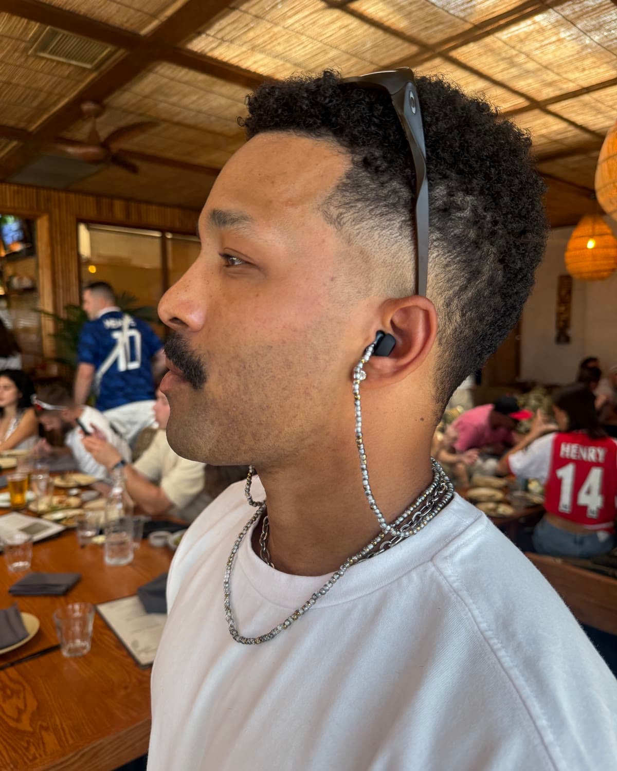 a silver chain running from the earplug in his ear down to his neck, seen from the side